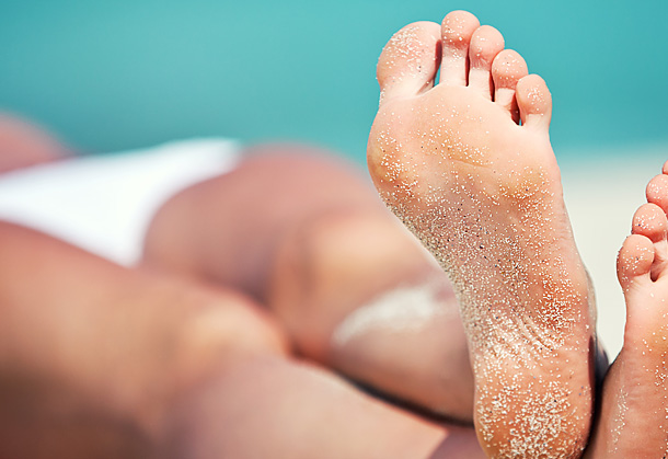 A colour image of the tanned legs and feet of a person lying on a beach after receiving spray tanning by Vicki Hooper Beauty - Grayshott & Headley Down